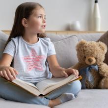 Kind mit Buch und Teddy